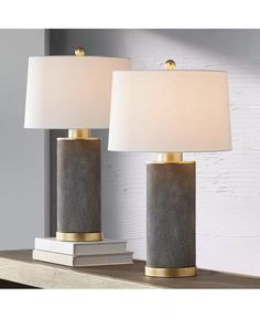 two lamps sitting on top of a table next to a white book and lamp shade