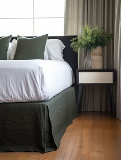 a bed with white sheets and green pillows