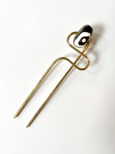 a pair of scissors sitting on top of a white table next to a hair pin