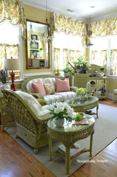 a living room with wicker furniture and flowers on the coffee table in front of it