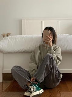 a woman sitting on the floor with her phone up to her face, taking a selfie