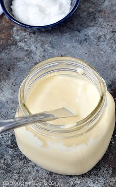 a jar filled with cream sitting on top of a table next to a bowl full of sugar