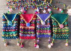 several colorful purses are lined up on the floor with beads and buttons hanging from them