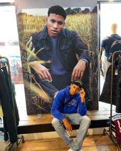 a man sitting on a bench in front of a large poster with an image of him