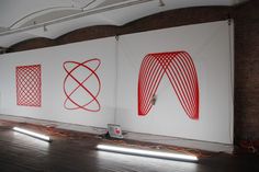 three large red and white paintings are on display in an empty room with wooden floors