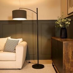 a living room with a white couch and a black lamp on the floor next to it