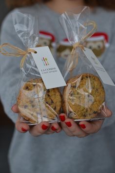 a woman holding two cookies wrapped in plastic