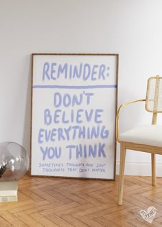 a framed poster sitting on top of a hard wood floor next to a white chair