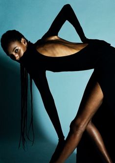 a woman in black is posing with her legs spread out to show off her body