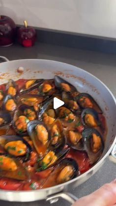 a pan filled with mussels and sauce on top of a stove