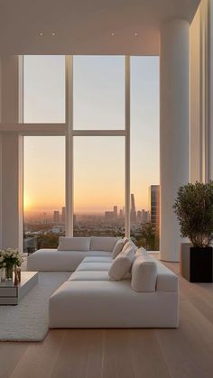 a living room filled with white furniture next to large windows and a view of the city