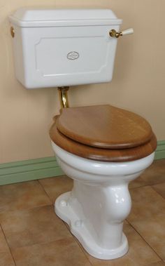 a white toilet sitting in a bathroom next to a brown tiled floor and beige walls