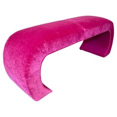 a pink bench that is shaped like a curved couch with an extended foot rest on it