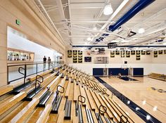 an empty basketball court with wooden benches and railings