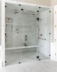 a bathroom with marble floors and walls, including a walk - in shower stall that has glass doors on both sides