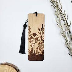 a wooden bookmark with an image of mushrooms on it and a tassel hanging from the front