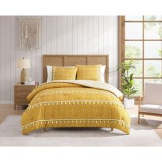 a bed with yellow comforter and pillows in a room