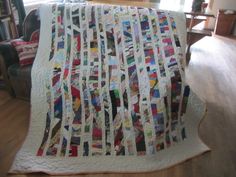 a white quilt with many pictures on it sitting on top of a wooden floor next to a chair