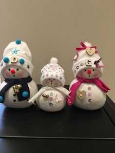 three snowmen with hats and scarves on sitting next to each other