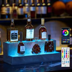 an assortment of liquor bottles are displayed on a table next to a cell phone and remote control