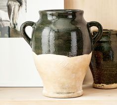 two black and white vases sitting on top of a wooden table next to each other