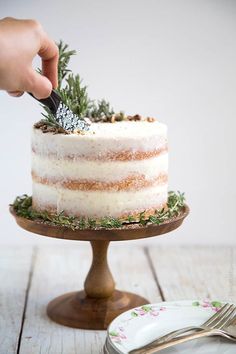 a person cutting into a cake with a knife and fork on a wooden table next to a plate