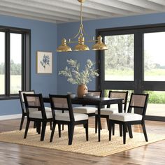 a dining room with blue walls and wooden flooring is pictured in this image, there are many chairs around the table