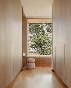 an empty room with wooden floors and white walls, looking out onto the trees outside