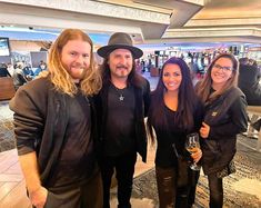 three people standing next to each other in front of a bar smiling at the camera