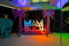 a neon sign that reads miami beach in front of some palm trees and lights at night