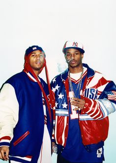 two men standing next to each other in front of a white wall with an american flag on it