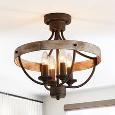 a wooden chandelier with three lights hanging from it's center beam in a living room