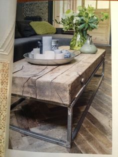 a wooden table topped with a bowl of flowers next to a couch and coffee table