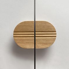 a round wooden object hanging from a metal rod on the wall next to a white wall