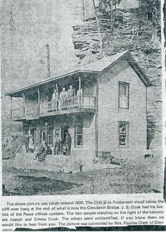 an old black and white photo of people on the porch of a house with a cliff in the background