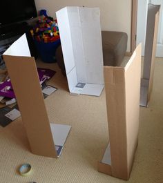 two cardboard boxes sitting on the floor in front of a flat screen tv and toys