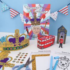 a table topped with paper cut outs and scissors next to a card, crown, and other items