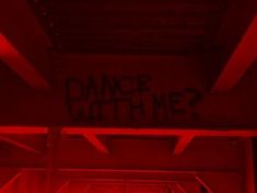 a red room with graffiti written on the ceiling and walls, which reads dance both me?