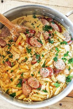 a pan filled with pasta and sausage on top of a wooden table