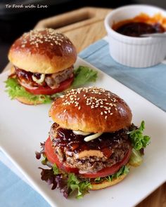 two hamburgers sitting on top of a white plate