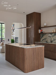 a modern kitchen with marble counter tops and wooden cabinetry, along with an open floor plan