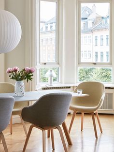 a dining room table with four chairs and a vase filled with flowers on top of it