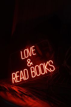 a neon sign that says love and read books in red letters on a black background