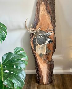 a wood carving of a deer with antlers on it's head is next to a potted plant