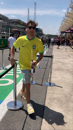 a man in yellow shirt and shorts standing next to fence