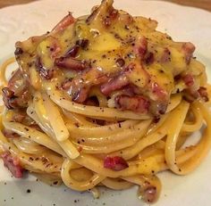 a white plate topped with pasta covered in cheese and bacon on top of it's own