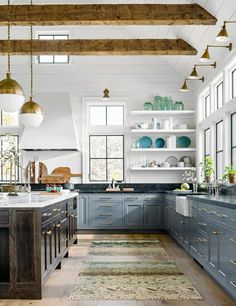 a large kitchen with blue cabinets and white counter tops, gold pendant lights over the island