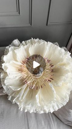 a large white flower sitting on top of a bed