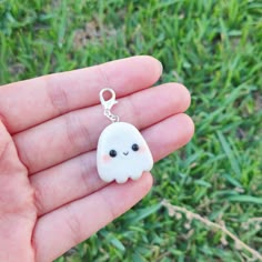 a hand holding a small white charm with a ghost face on it's side