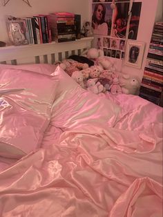 there is a bed with pink sheets and stuffed animals on the bottom half of it